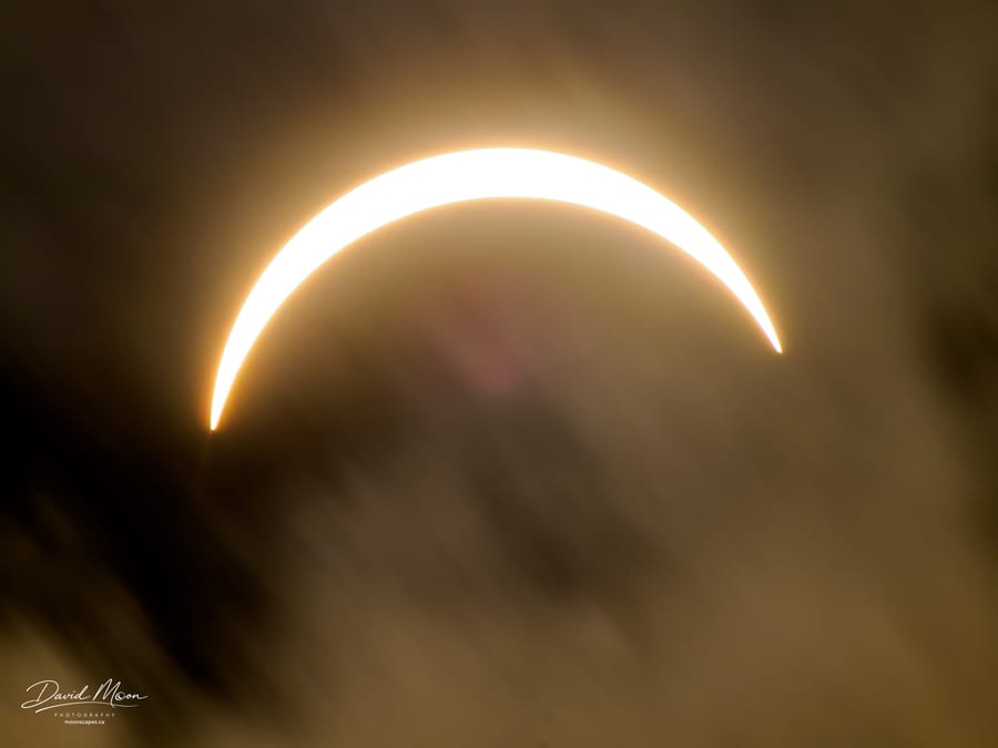 Crescent Sun Through Moving Clouds